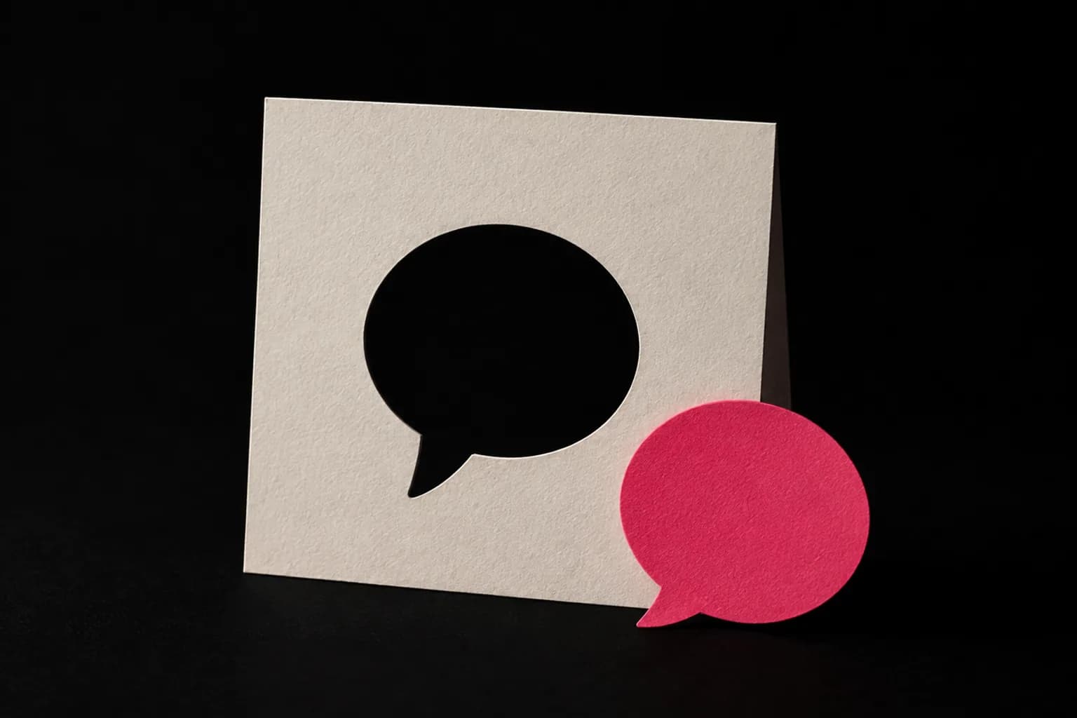 A paper dictionary card with a single word cut out of it, and a small confident speech bubble leaning against it.