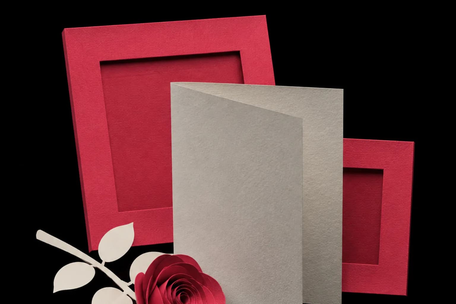 Two paper photo frames, one partly covered by a cream card.