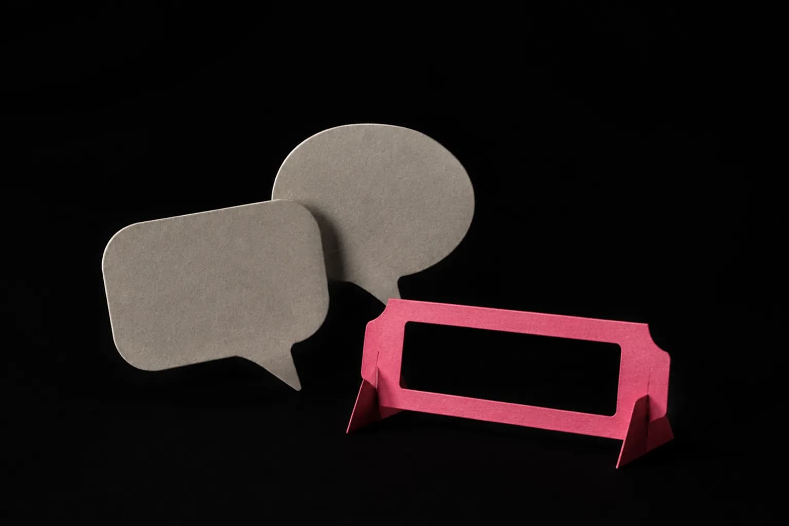 Two paper speech bubbles beside an open cardboard label holder.